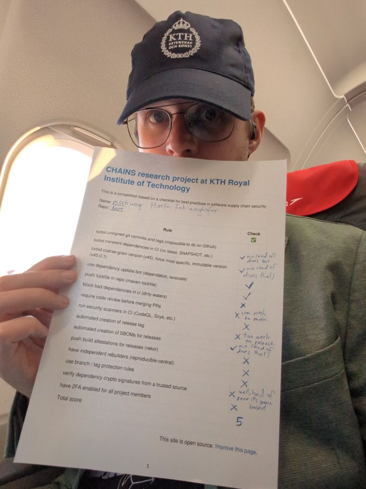 Me, a male human, in my bodily form, sitting in one of the window seats of an airliner, wearing a KTH hat and holding my filled-out best practices in software supply chain security self-assessment sheet, obscuring my lower face and chest.