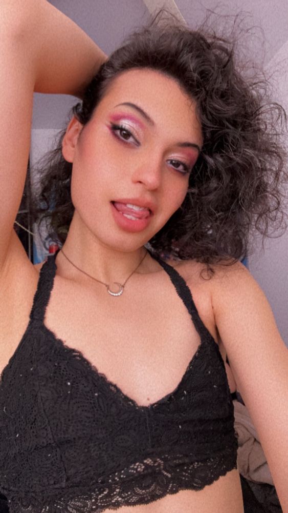 Pretty trans girl in black lace bra and curly hair with graphic pink makeup 