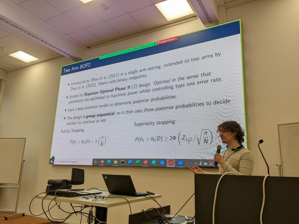 Photo of Connor Fitchett giving a presentation with projector screen of slide behind them. 