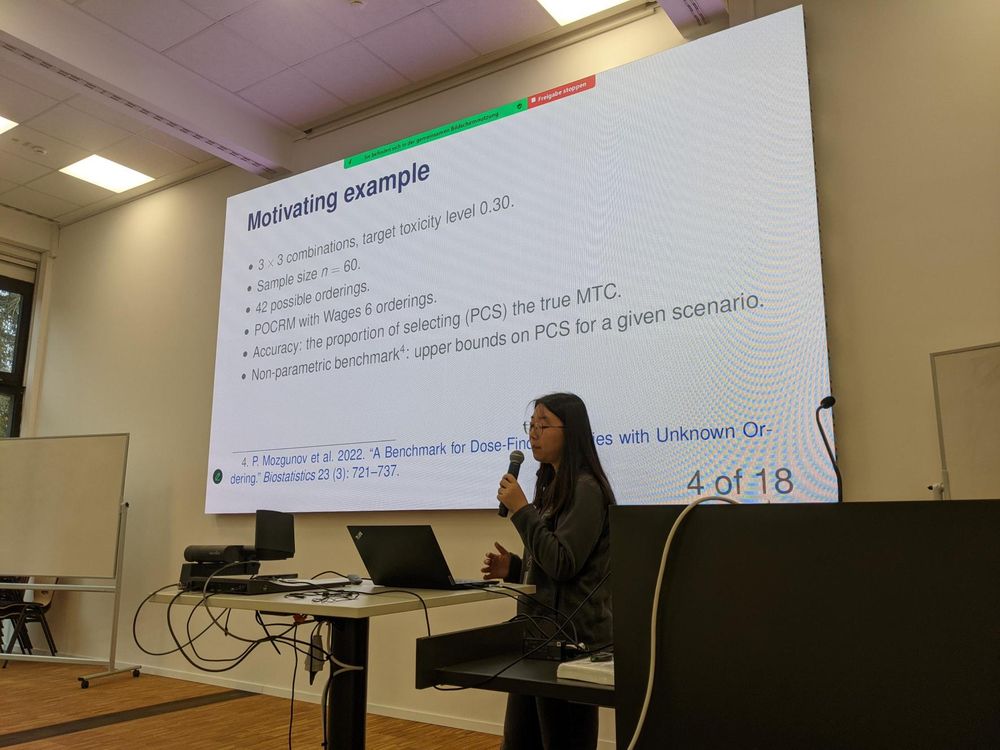 Photo of Weishi Chen giving a presentation with projector screen of slide behind them. 