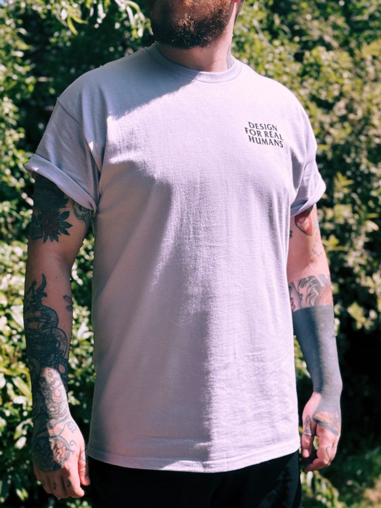 A man outdoors wearing a t-shirt that says 'Design for Real Humans'