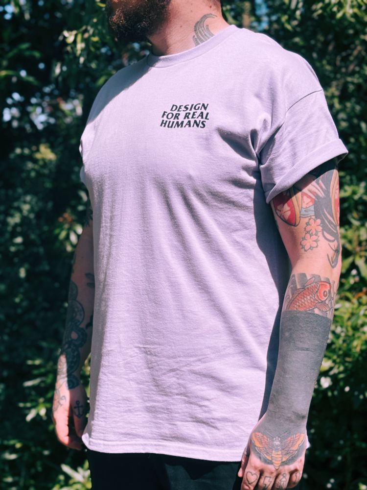 A man outdoors wearing a t-shirt that says 'Design for Real Humans'