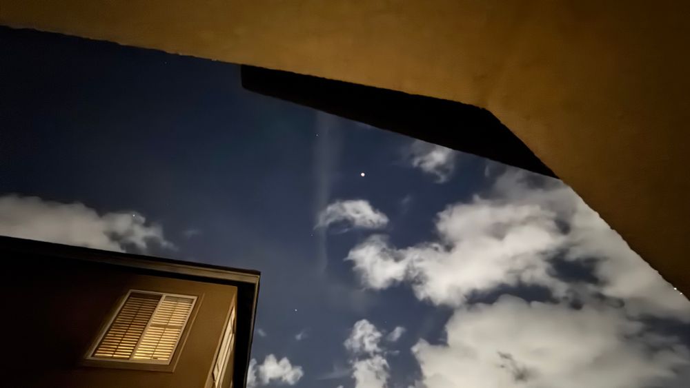 Photo of the lunar eclipse on 13 March 2025 from my porch. Clouds from an earlier weather system are scattered near the moon. iPhone 15 Pro Max 0.5x wide angle.