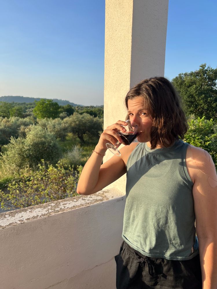 The author looking skeptical while drinking a glass of wine on an Italian balcony in the evening sunlight 