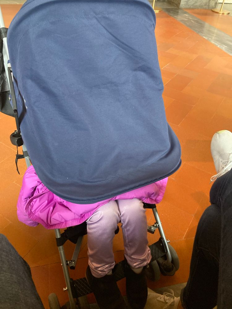 Child in stroller with shade down showing only her feet