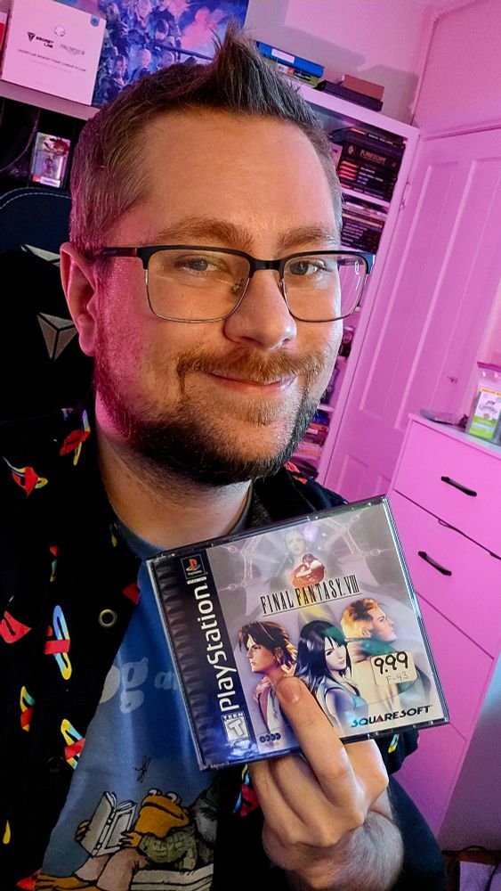 Person smiling with glasses holding up a copy of final fantasy eight on the p.S one