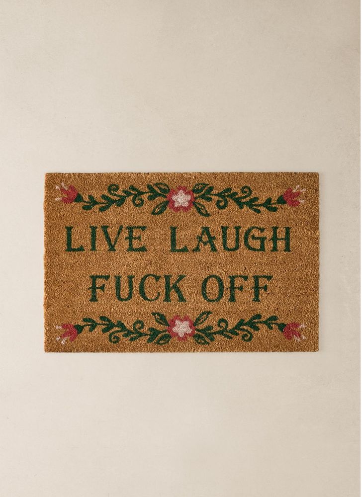 eine fußmatte mit dem aufdruck „live laugh fuck off“ und zwei blumenranken