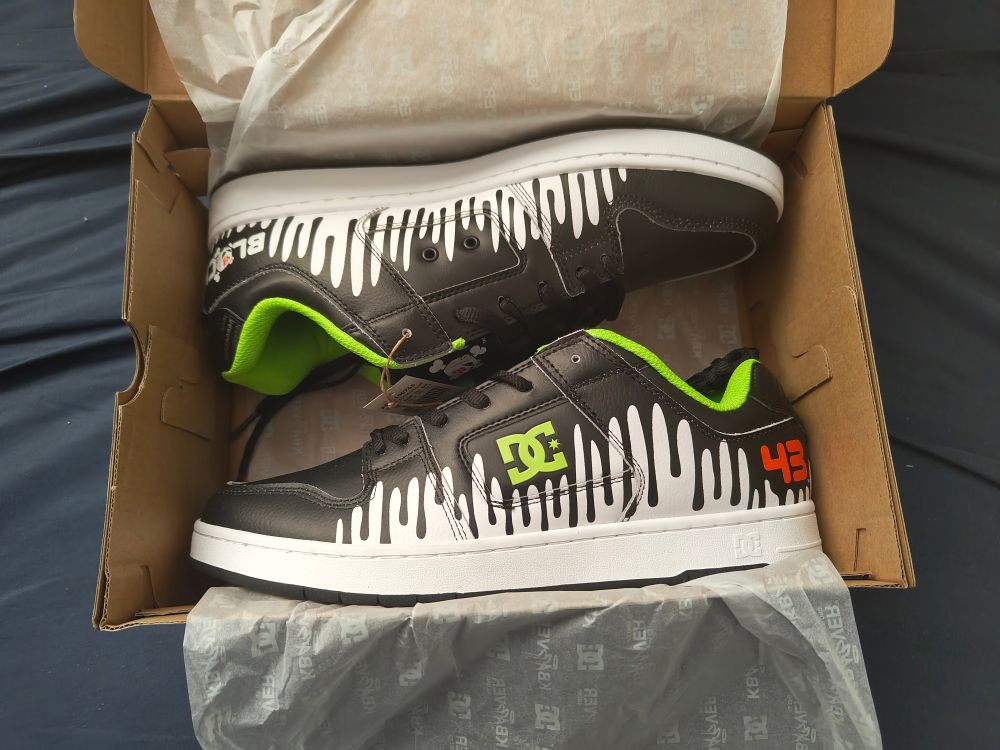 Una vista a las zapatillas DC Manteca de edición especial en memoria de Ken Block. El diseño en blanco y negro, con acentos en verde, también incluye por un lado el número 43 en naranja, y el logo propio de Ken Block. Es un diseño inspirado en el Ford Fiesta de rally de Ken Block usado para su iconico video Gymkhana 3.