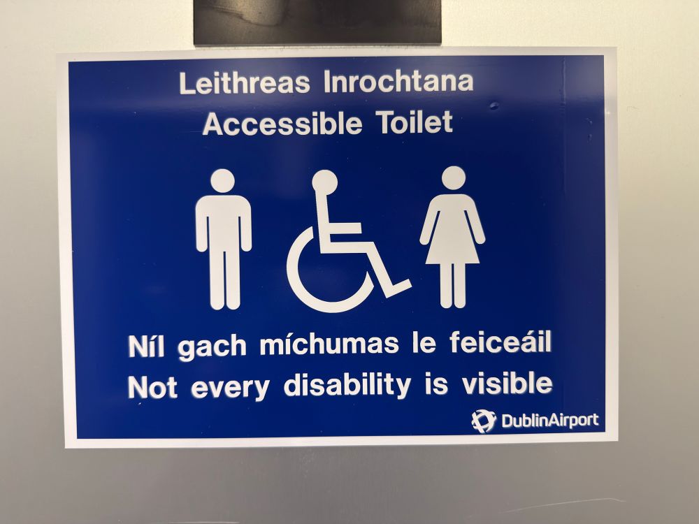 Sign in Gaelic and English that says:

- Leithreas Inrochtana / Accessible Toilet
- Níl gach míchumas le feiceáil/ Not every disability is visible