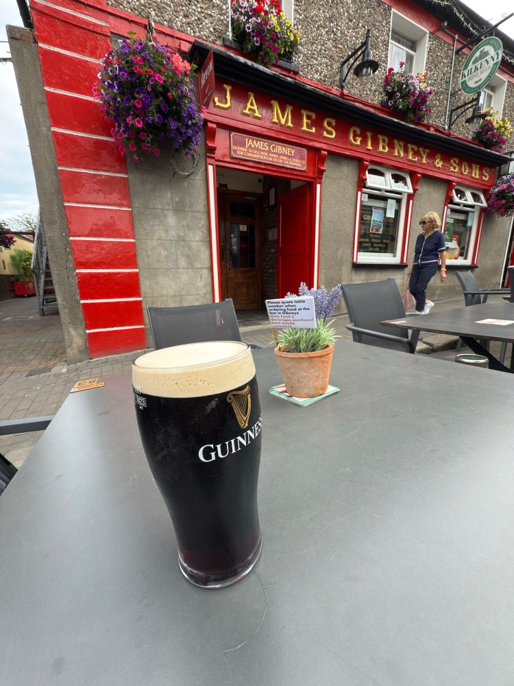 Photo of a pint of non-alcoholic Guinness on a patio outside of an Irish pub. The kind of Irish pub you find in Ireland.