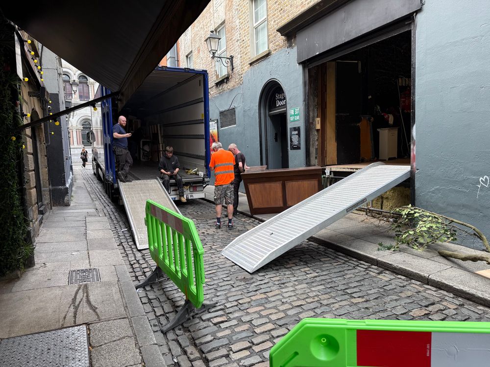 Photo of workers moving stage equipment into the back of a truck.

The truck is taking up nearly the entire width of the street, but because there are so few cars in the area, it’s not causing car traffic chaos and the moving of materials into the truck can happen safely.