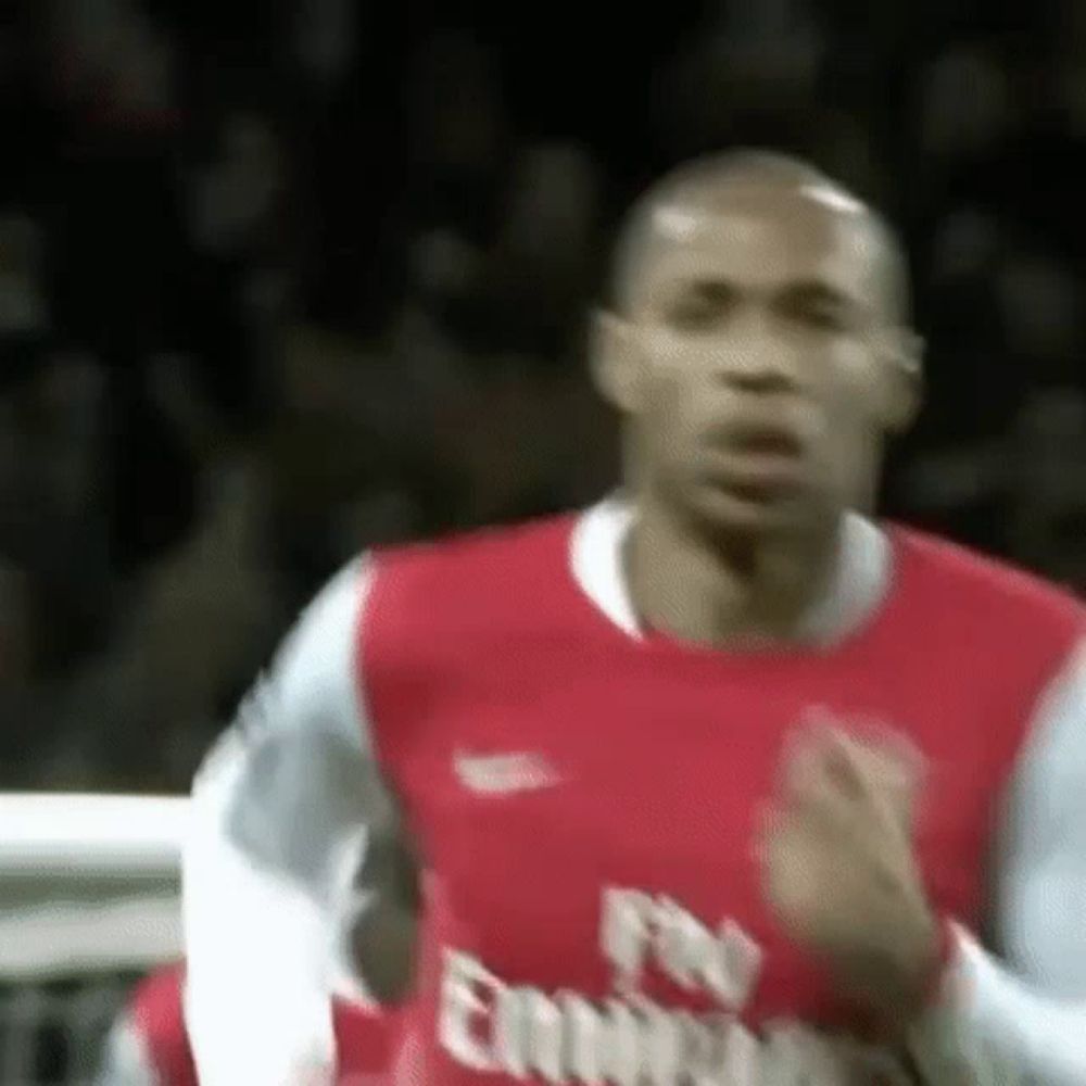 a soccer player wearing a red fly emirates jersey is running on a field .