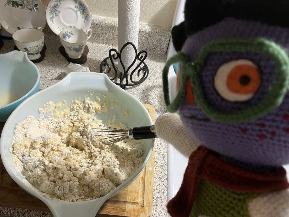 a plush half demon looks at the camera as he whisks dough