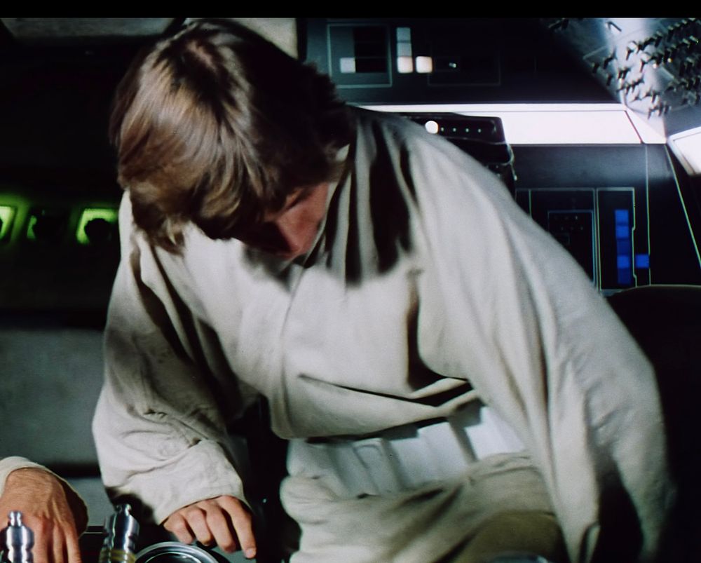 Luke sitting down in the Falcon cockpit, his poor fashion choice clearly visible around his waist.