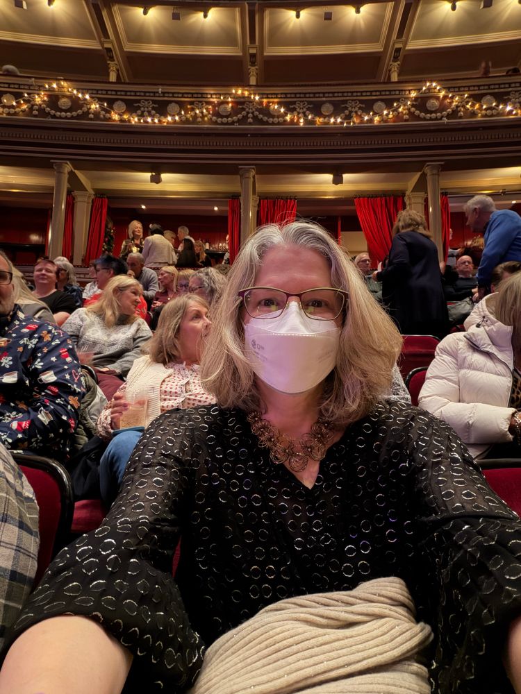 Picture of a woman in a dressy top at the Royal Albert Hall in London at a Christmas event, wearing an N95 