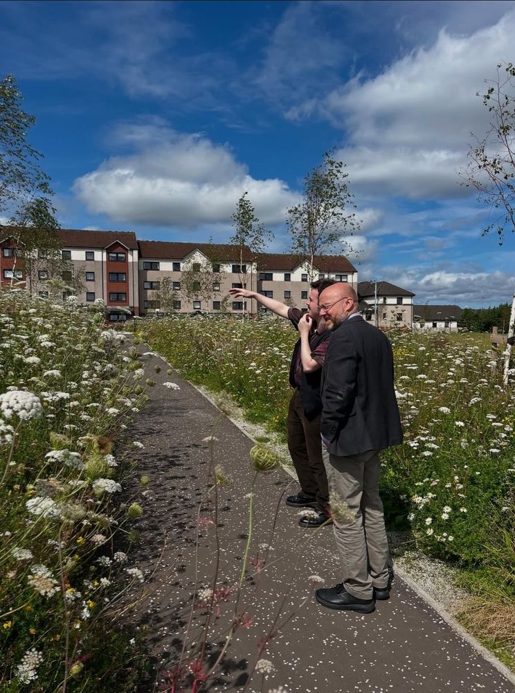 Anthony pointing out wildflowers to Patrick in a greenspace developed on Roystonhill.