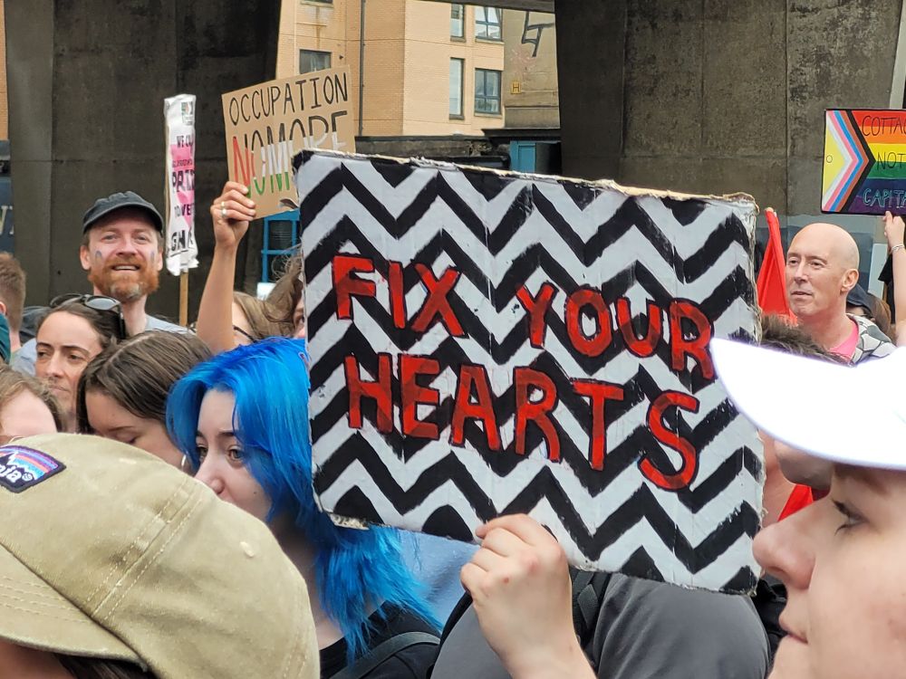 Sign held up that says fix your hearts, with the red room floor design behind from Twin Peaks