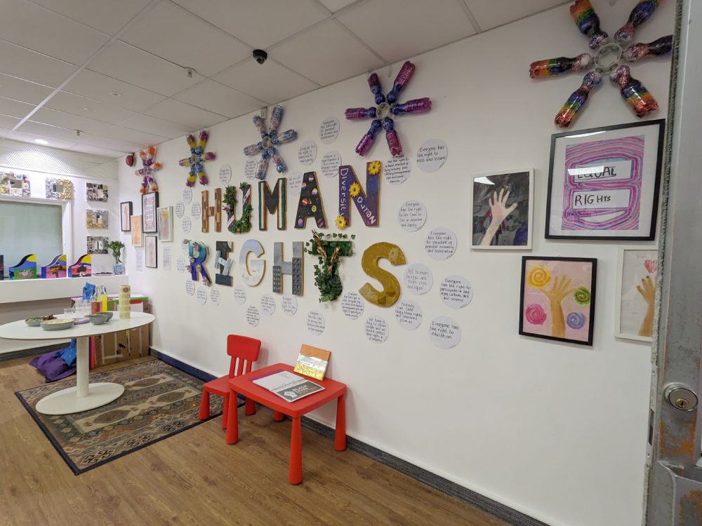 wall of exhibition space with HUMAN RIGHTS in colourful decorated letters surrounded by bubbles containing text of the Rights