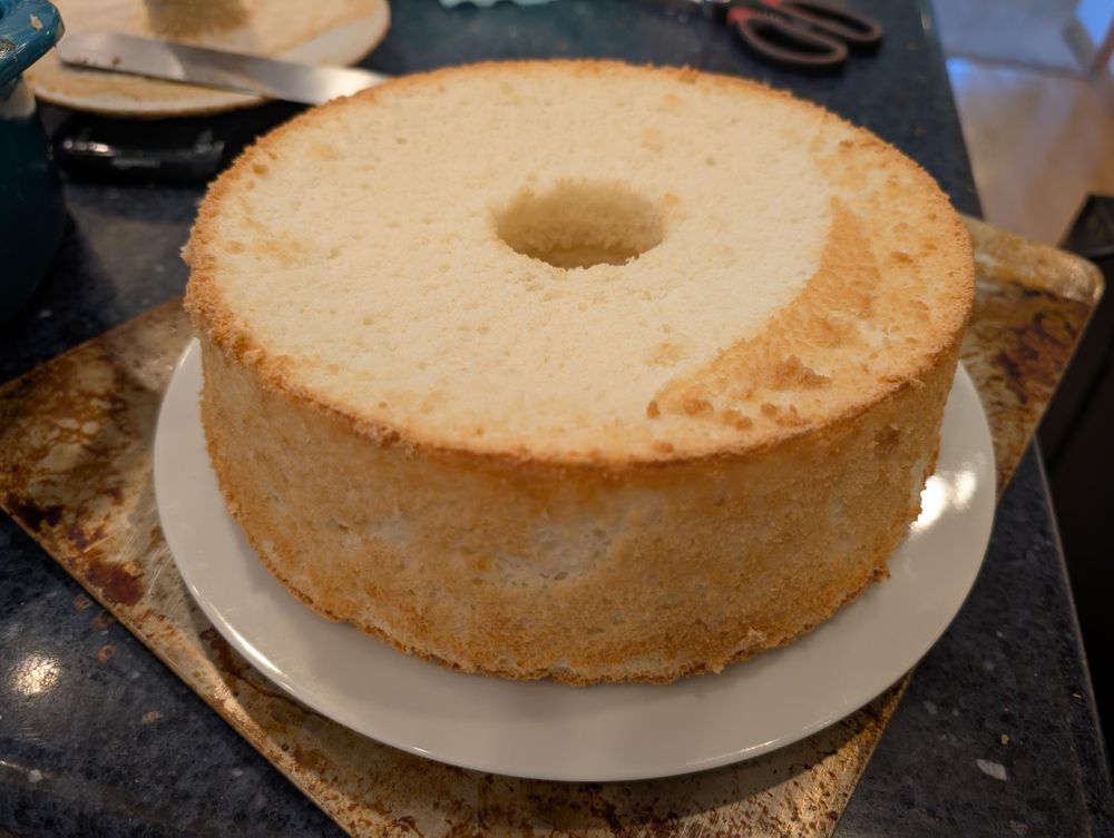 A photo of an upside down angel food cake, an extremely light and fluffy, unadorned circular cake with a hole in the middle.