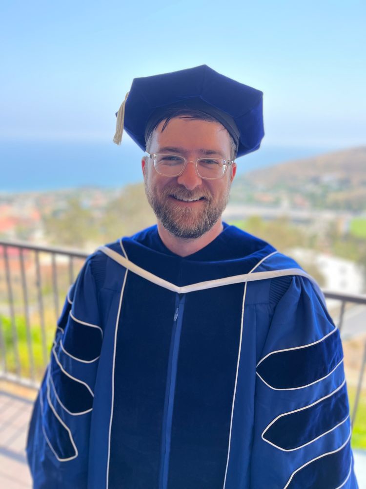 Man wearing blue PhD robes. 
