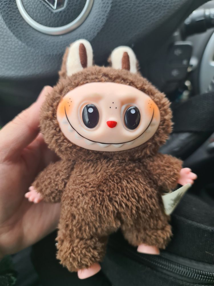 Un moñeco labubu de esos. De color marrón 