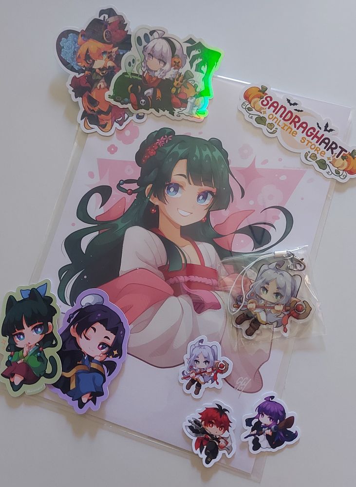 Una print de Maomao, un llavero de Frieren y varios stickers de la artista SandraGH