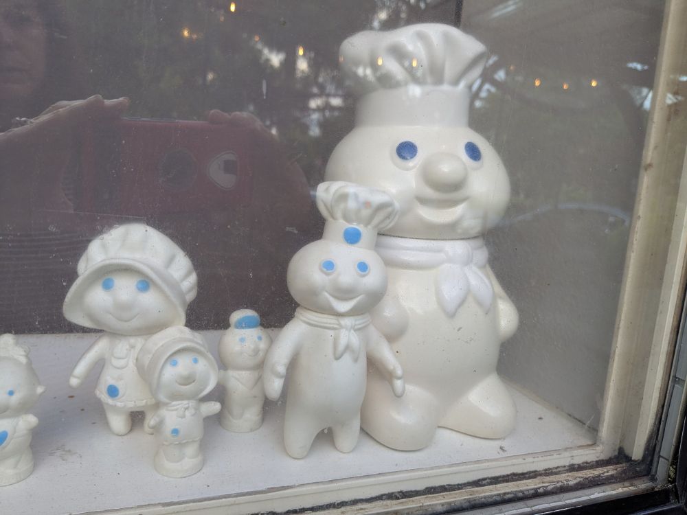 Collection of Pillsbury Dough Boy toys in shop front window. 