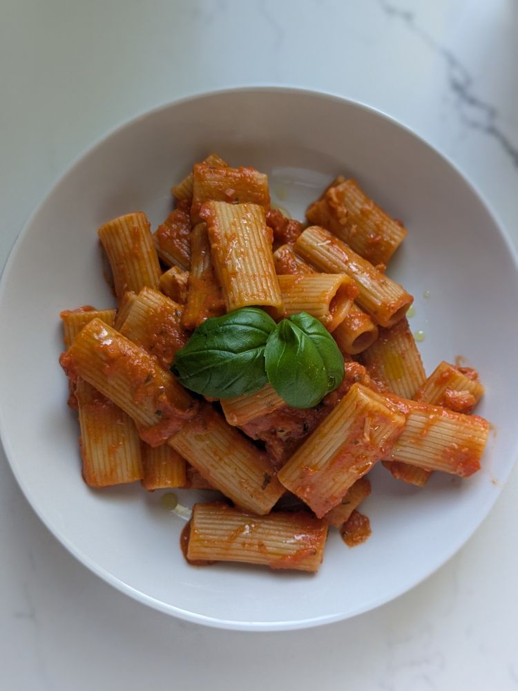 Rigatoni coated in creamy vodka tomato sauce with basil leaves on top. 