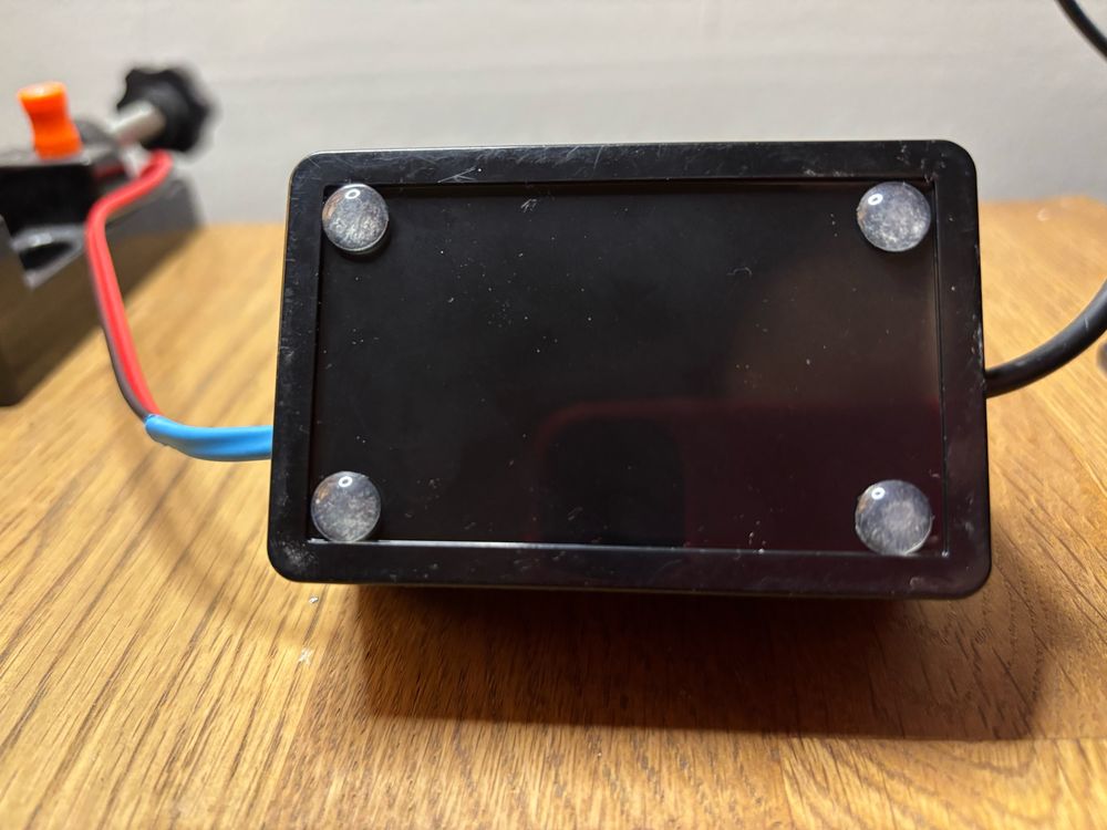 Small black box with tacky feet attached in the corners on the corner of a desk 