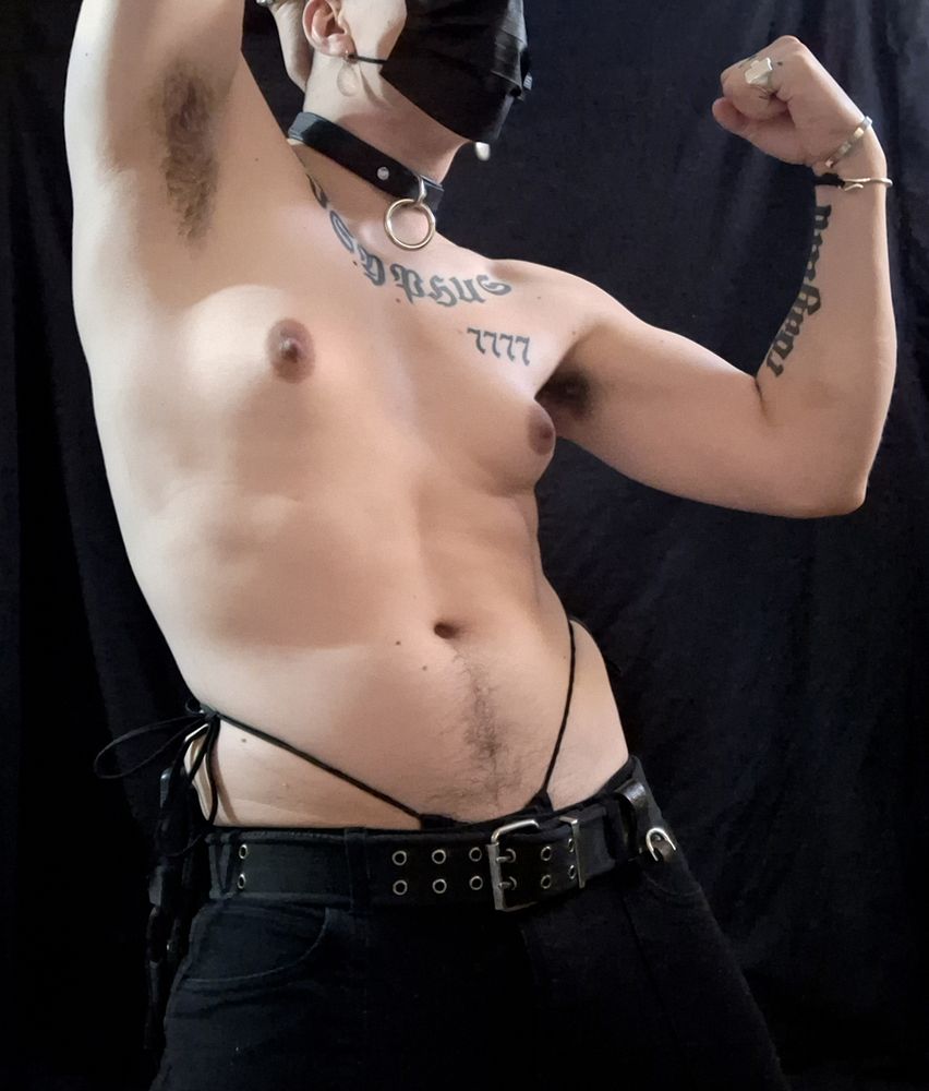 A pic of Ashe looking like a total butch dyke. She's wearing black cargo pants with a military belt, with a black bikini bottom rising up over her hips, and a black leather collar. Her boobs look modest but tender and suckable, and she's flexing her bicep with her other arm behind her head in a way that shows off her hairy fuzzy musky sweaty armpits.