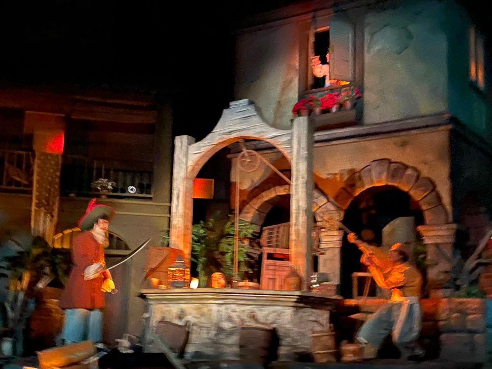 Two pirates attempting to drown a man named Carlos, while his wife looks on in horror through the shutters of a second story window.  