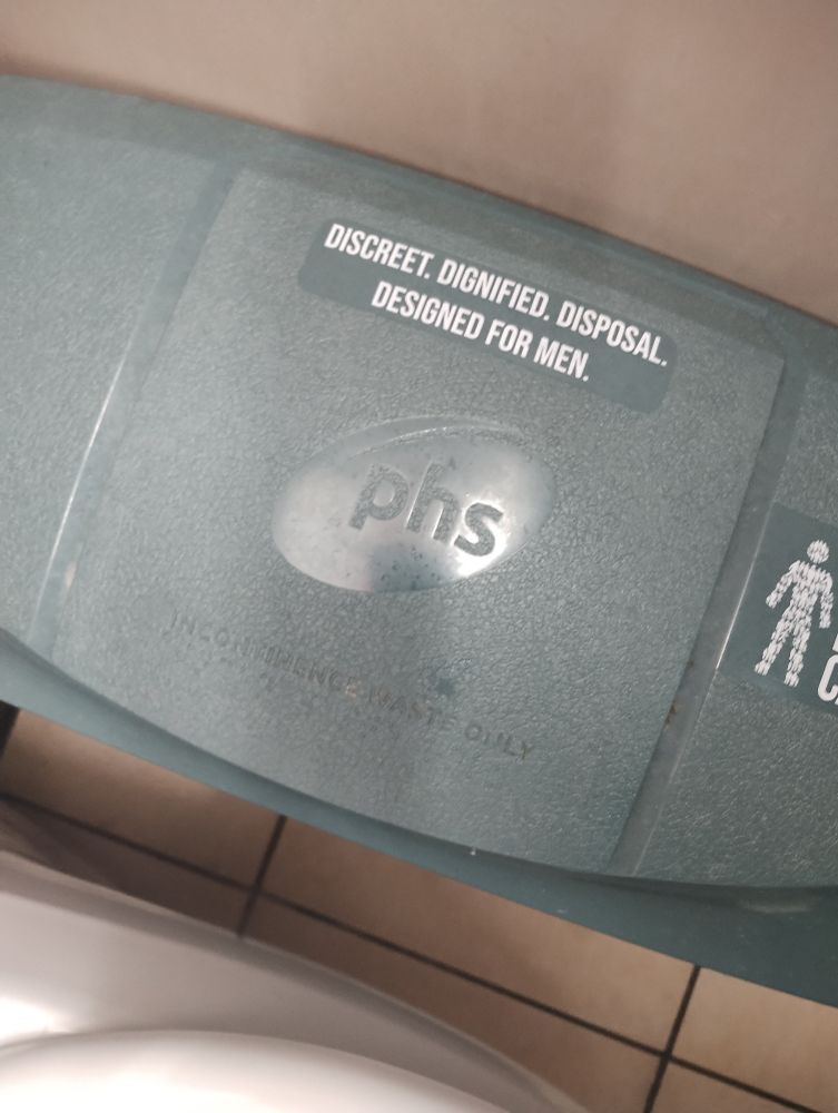 A sanitary waste bin labelled "Discreet. Dignified. Disposal. Designed for men." 