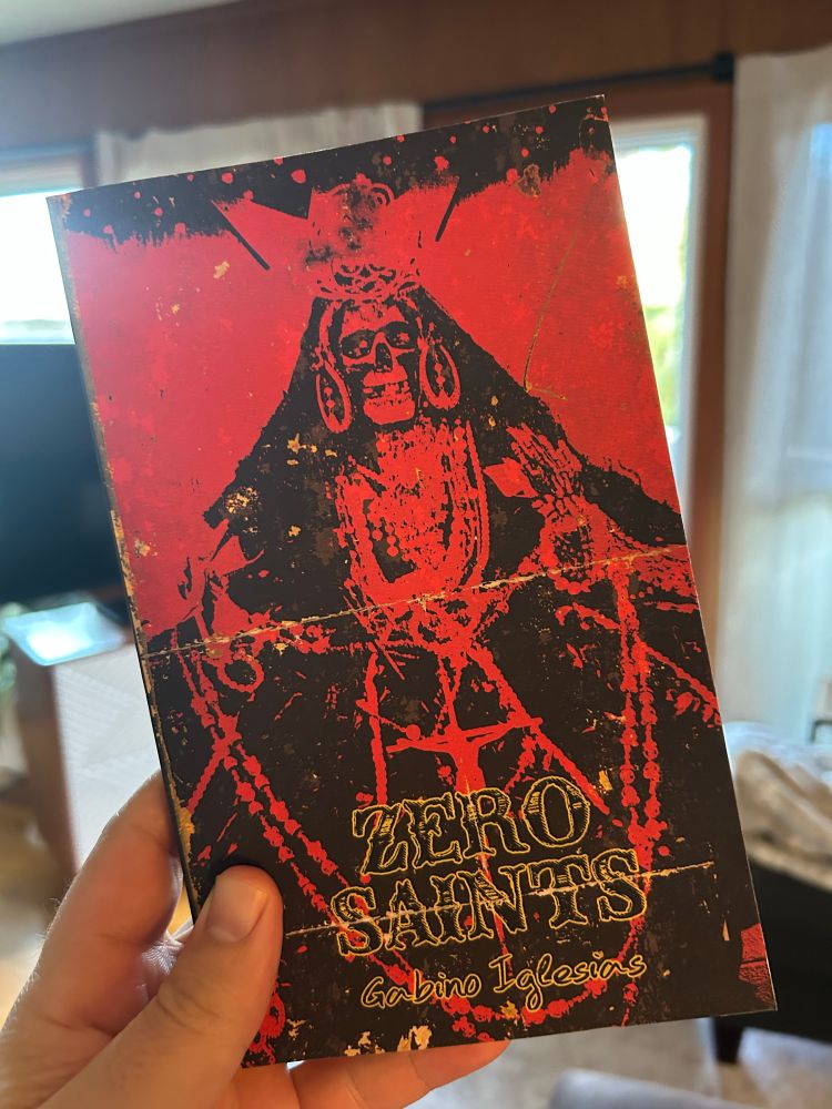 First edition of Zero Saints from Gabino Iglesias, featuring a red cover with a graphic of Santa Muerte.