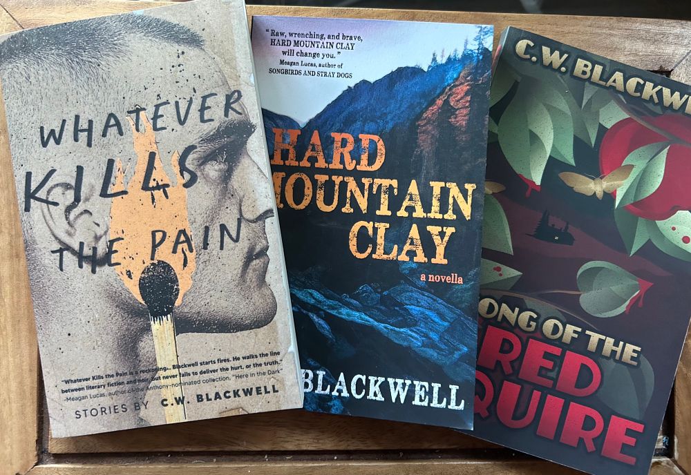 Three books on a table: WHATEVER KILLS THE PAIN, HARD MOUNTAIN CLAY, and SONG OF THE RED SQUIRE, by C.W. Blackwell.