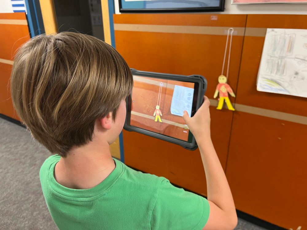student with iPad taking video and photos of the friction climbers to include in Canva presentation