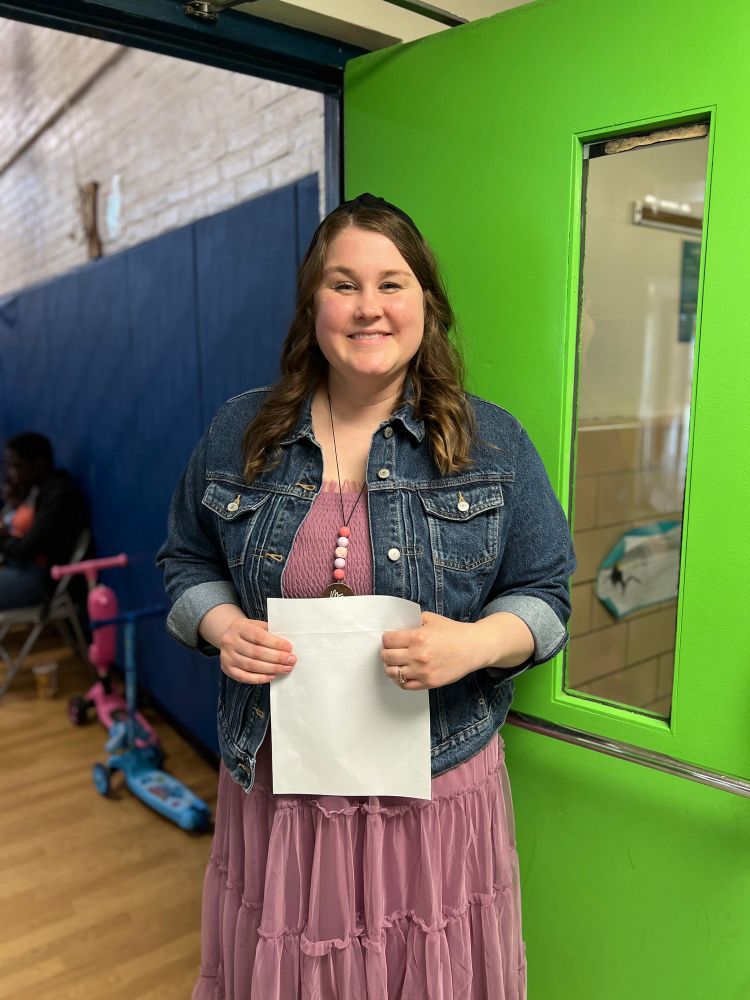 Music teacher Amanda Thiel greets students and families at the door to the gym. 