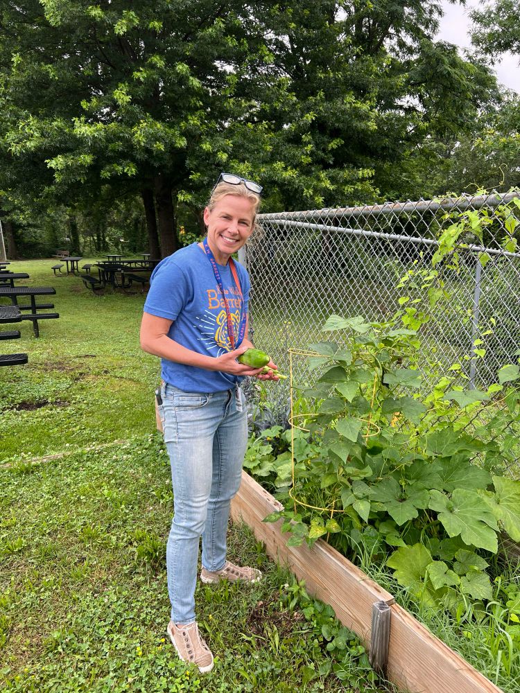 Science coach Carrie Lombardi checking on the garden beds of veggies and flowers 