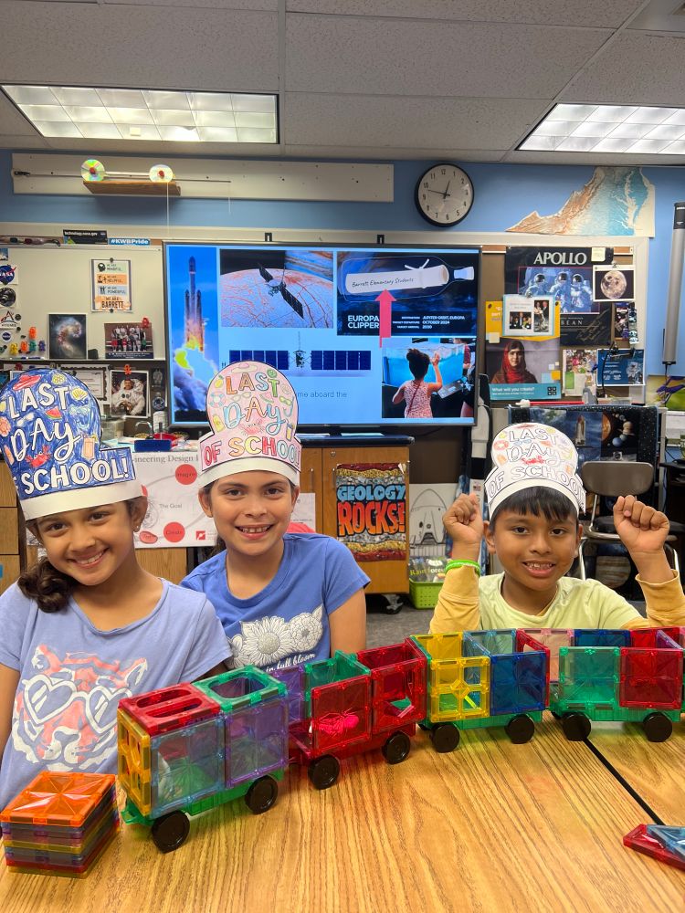 Students wearing last day of school hats working at the table with magnet blocks