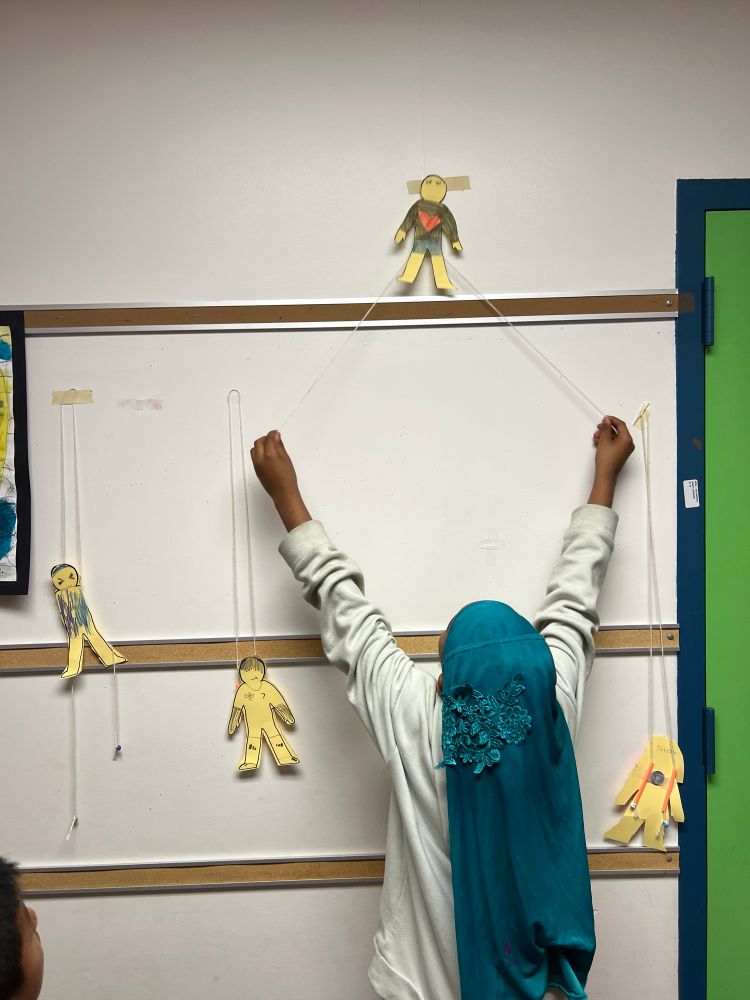 Student in the hall, pulling the string for her friction climber