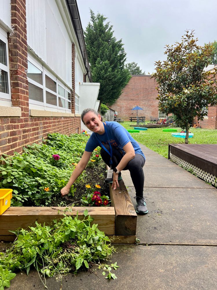 Project Discovery Teacher Stacey Fernandez weeds in the courtyard garden 