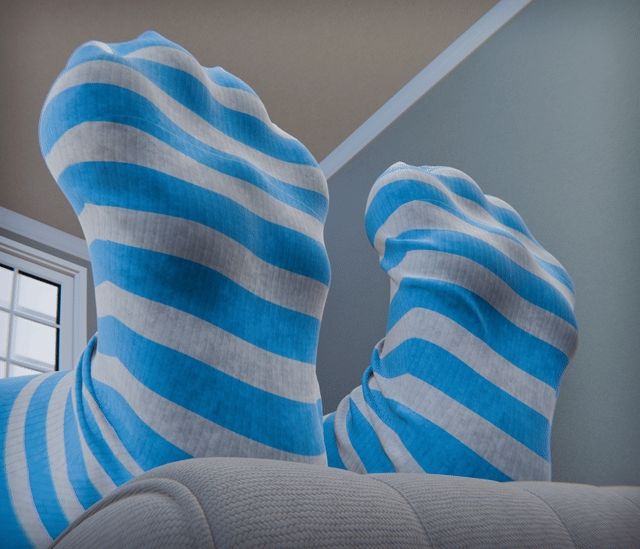 Gif of a pair of cats paws flexing their toes on the arm of a couch while wearing socks.