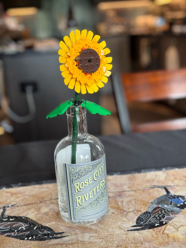 Our table’s centerpiece. A single LEGO sunflower in a Rose City Riveters labeled bottle. 
