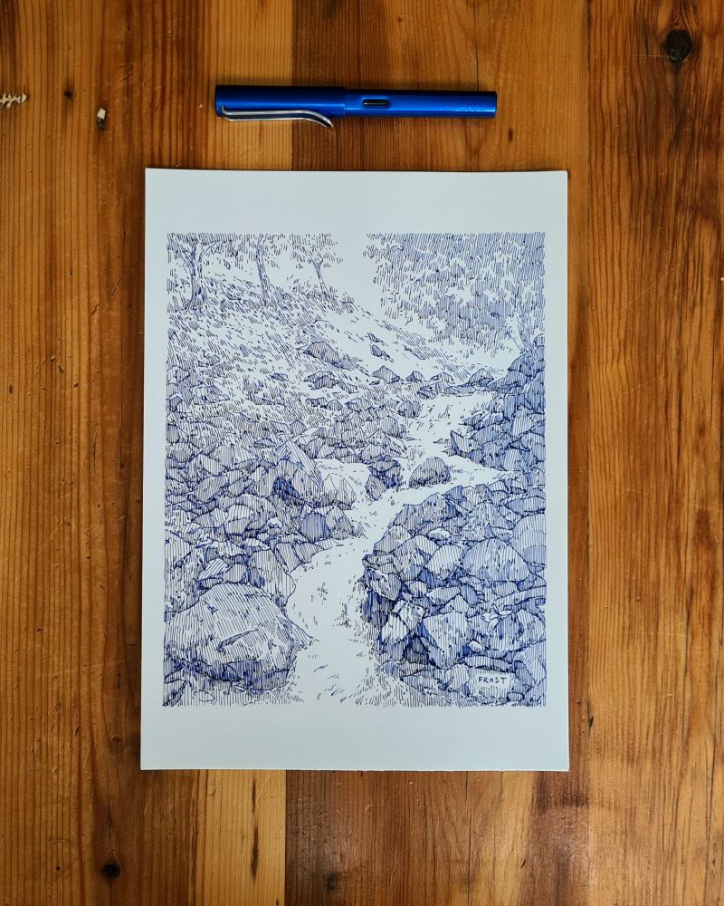A photo of an original fountain pen ink drawing on A4 white paper. The drawing is of a river and waterfall over rocks. It is monochrome blue and created with a fountain pen line hatching shading technique 