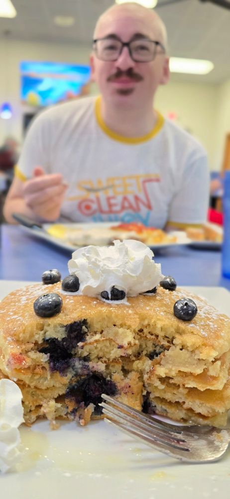 A stack of blueberry pancakes with Alec in the background looking adorable.