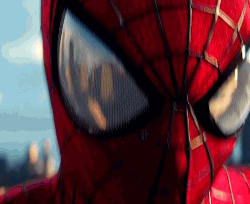 a close up of a spider man 's eyes with a city in the background