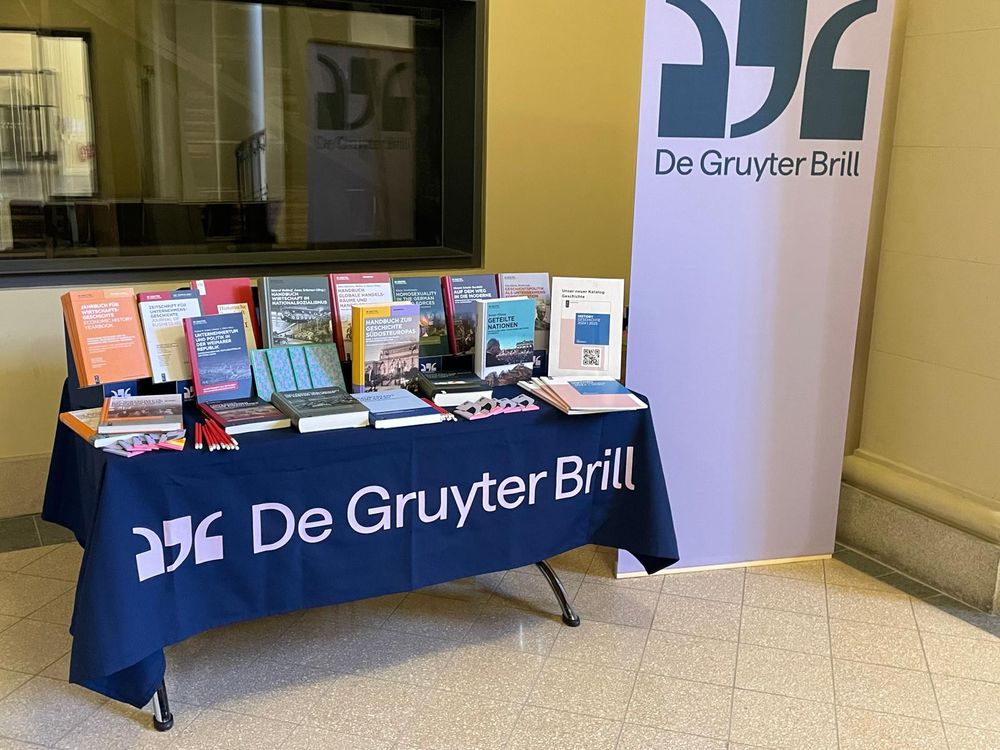 Büchertisch mit dem De Gruyter Brill Logo und verschiedenen Neuerscheinungen zum Thema Wirtschafts- und Sozialgeschichte.