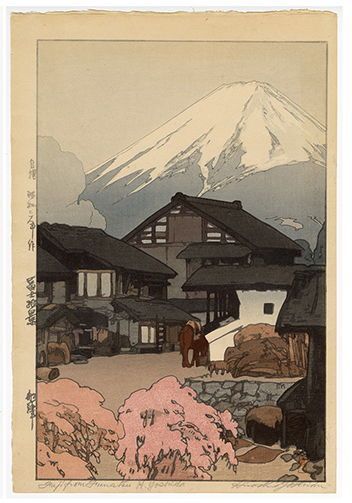 A color woodblock print of a few buildings in a village with cherry blossoms in the foreground and Mt. Fuji in the background.