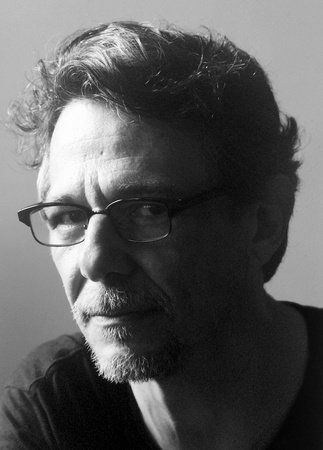 Black and white photo of Enrigue, looking at the camera with a serious expression, partially in shadow.