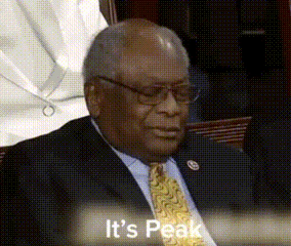 a man in a suit and tie is sitting in front of a sign that says it 's peak .