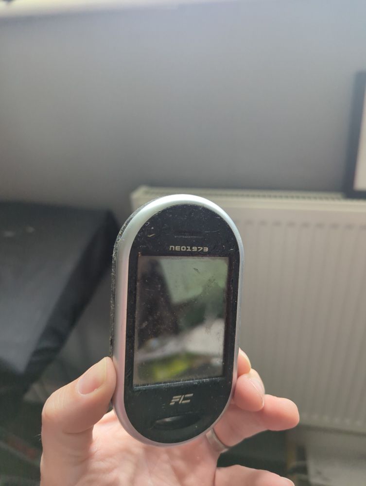 A hand holding up a very old FIC Neo1973 mobile phone prototype.